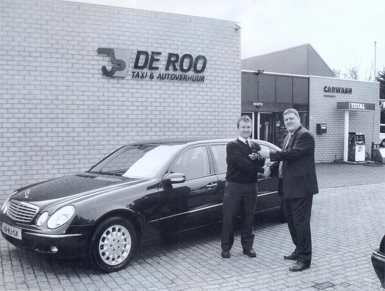 Historische foto van De Roo met een Mercedes en twee medewerkers voor het voormalige pand